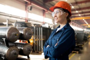 Mulher sorrindo de braços cruzados em uma indústria representando o GLP industrial