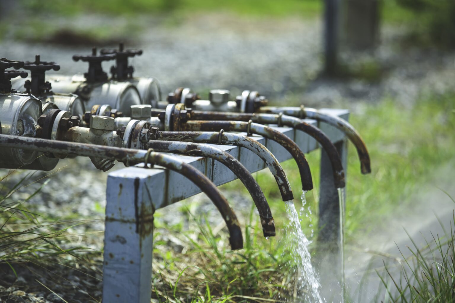 Sistema de irrigação mostrando bombeamento de água com mangueiras e válvulas atuando na irrigação de plantações verdes, promovendo agricultura eficiente e sustentável.